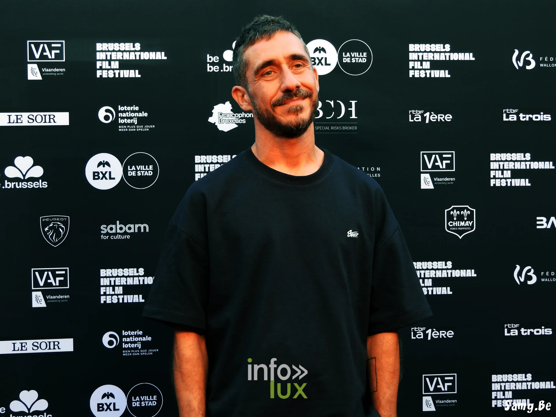 Un comédien de Vigilante en t-shirt noir devant le mur du festival
