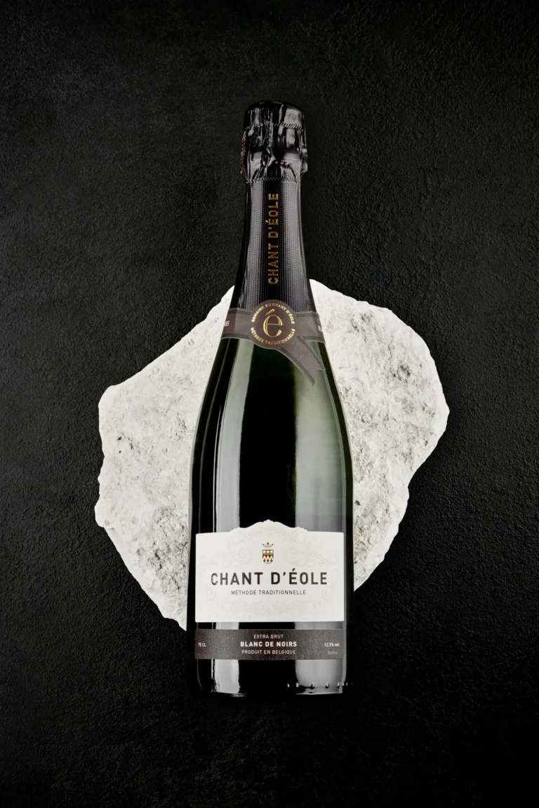 Bouteille du Blanc de Noirs du Chant d’Éole posée sur un bloc de craie, fond noir