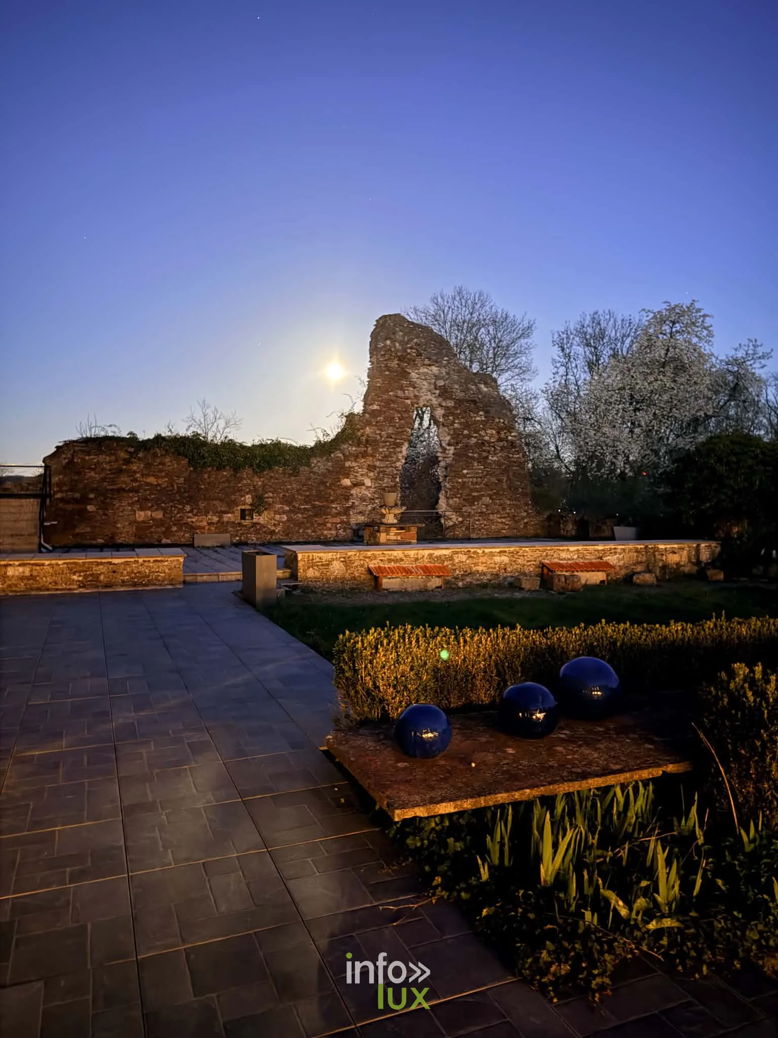 Les ruines du château de Latour éclairées sous la lune, terrasse et boules lumineuses bleues au premier plan