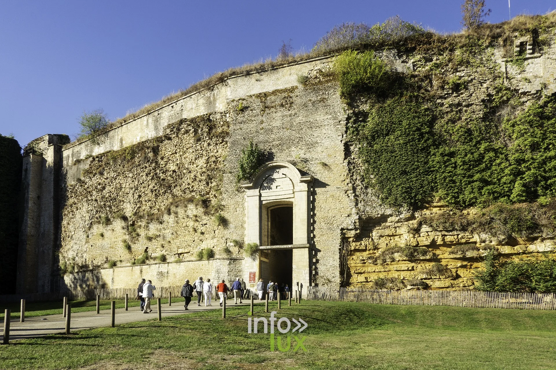 Porte monumentale percée dans la muraille du château fort de Sedan, pelouse au premier plan