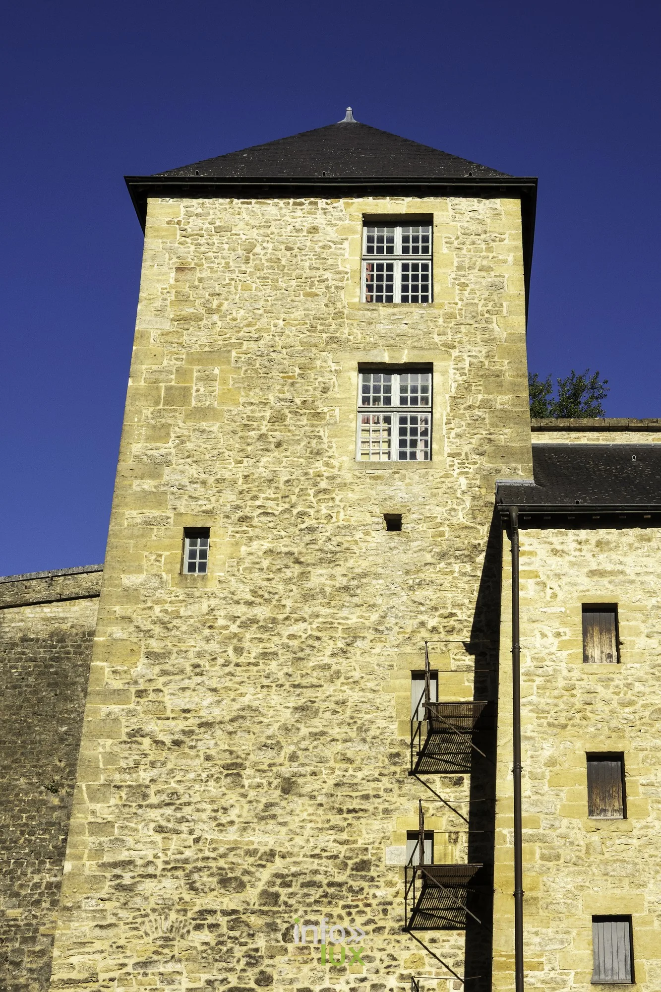 Tour carrée en pierre jaune du château fort de Sedan sous un ciel bleu