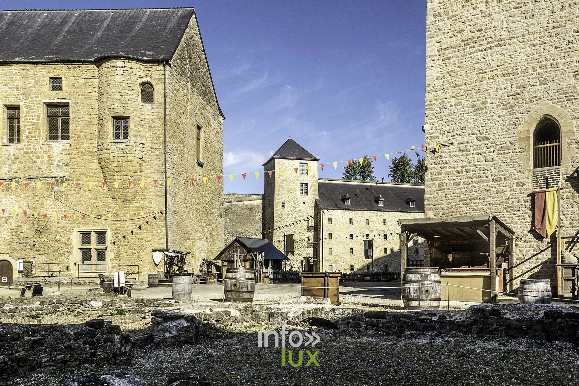 Cour du château fort de Sedan avec échoppes en bois, tonneaux et tour carrée au fond