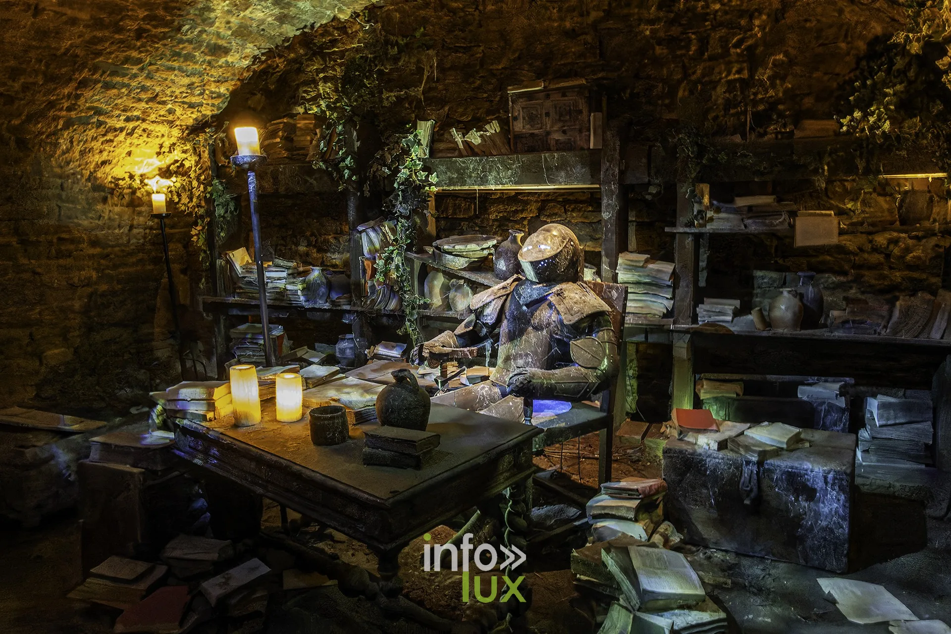 Salle voûtée reconstituée avec bibliothèque, bougies et armure assise, au château fort de Sedan (Ardennes)