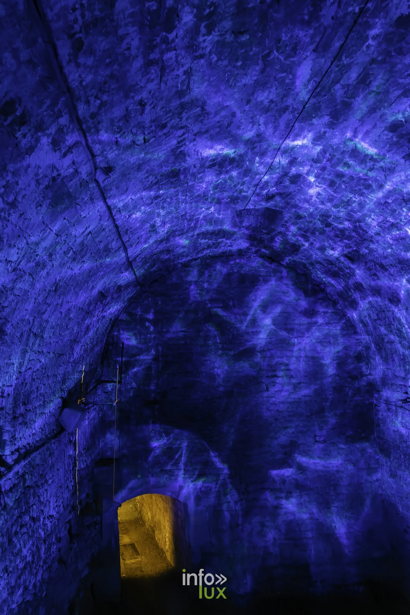 Couloir voûté éclairé en bleu dans le parcours de visite au château fort de Sedan (Ardennes)