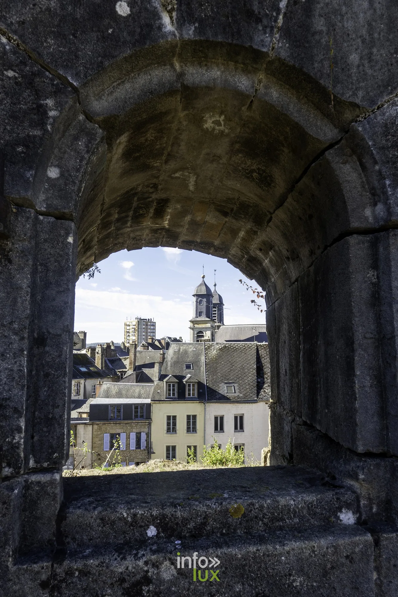 Embrasure voûtée du rempart cadrant les maisons et un clocher de Sedan