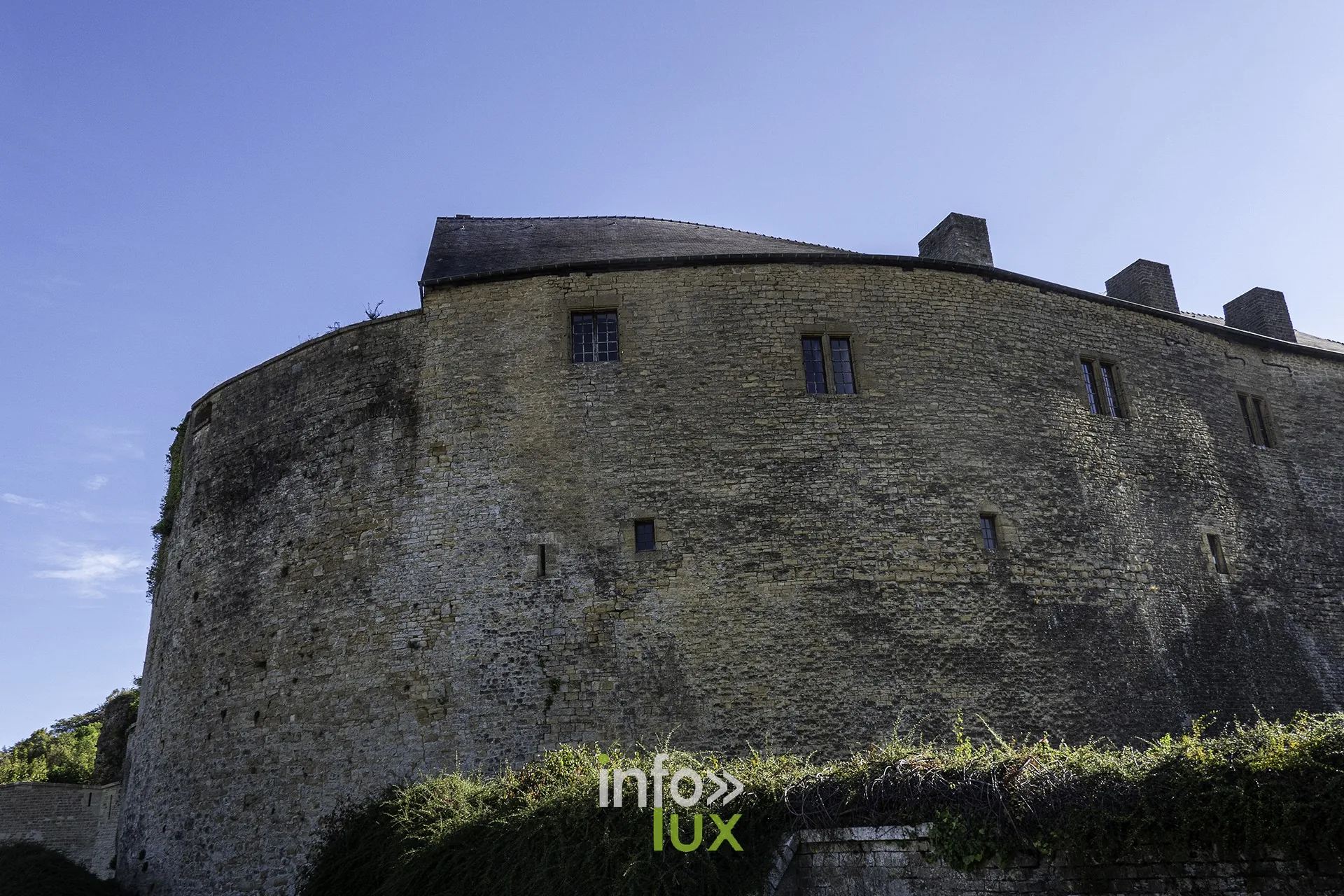 Muraille courbe et tour du château fort de Sedan au-dessus des fossés herbeux