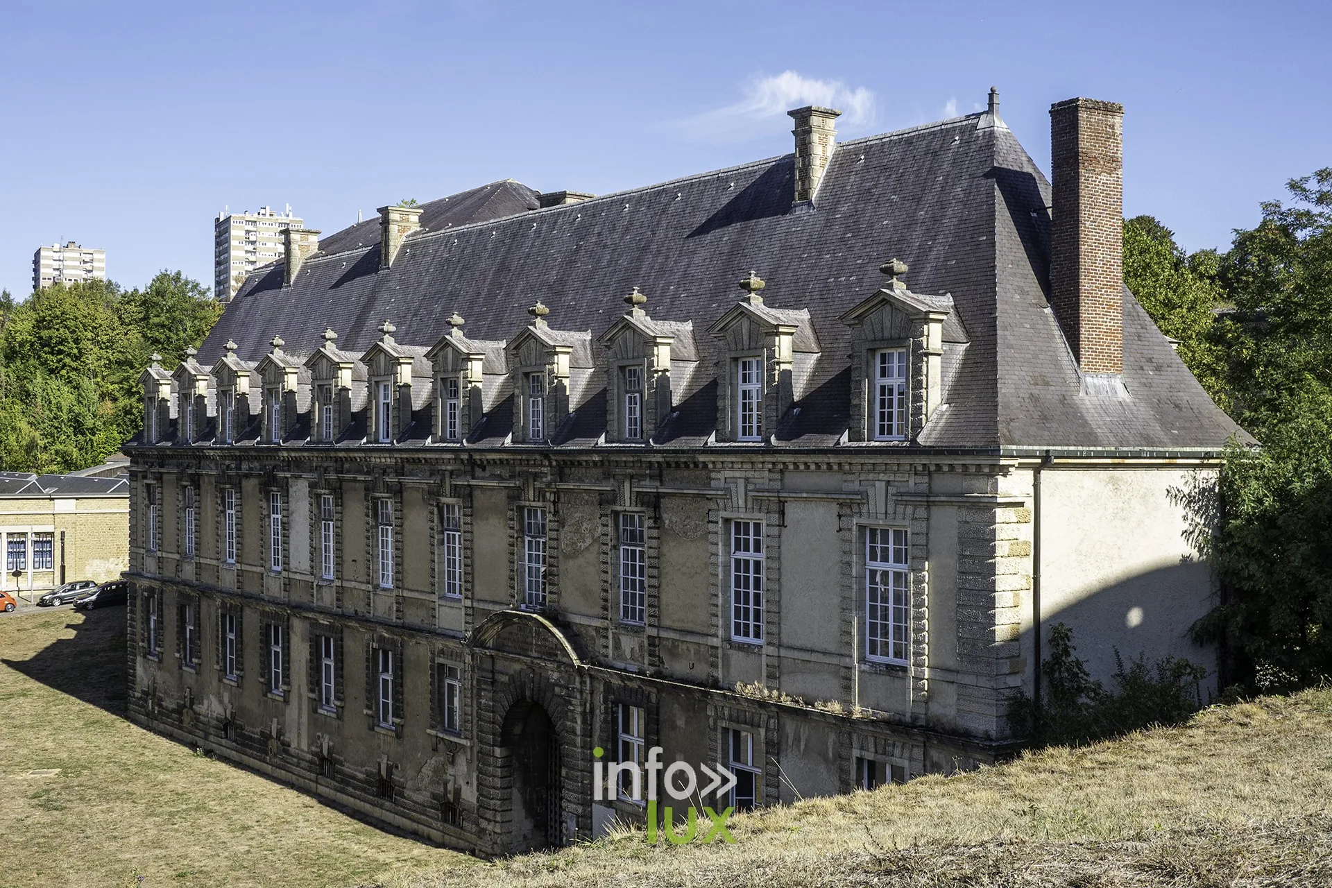 Bâtiment classique à lucarnes et haute cheminée au pied du château fort de Sedan