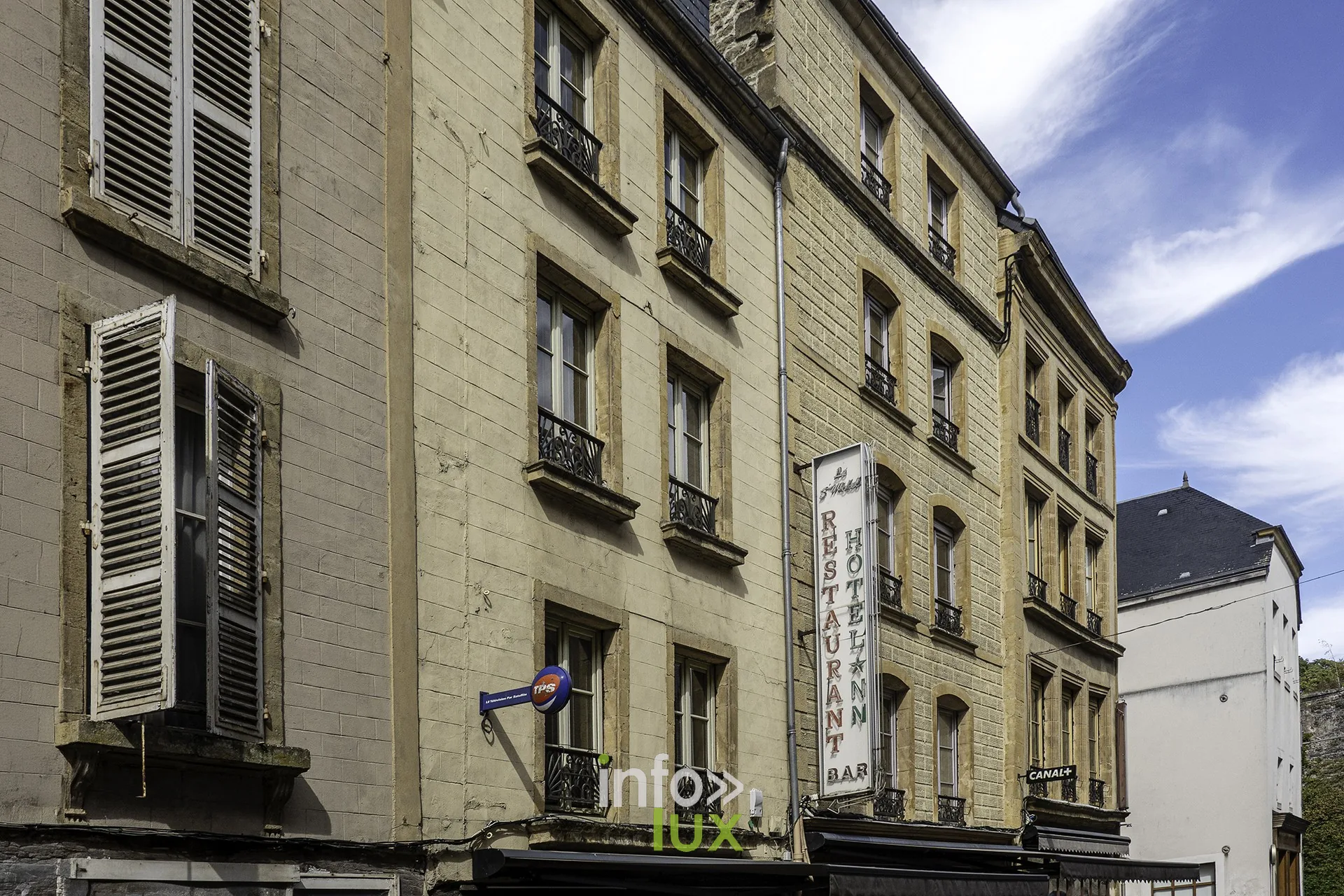 Façades d’immeubles anciens avec volets et enseigne d’hôtel dans une rue de Sedan