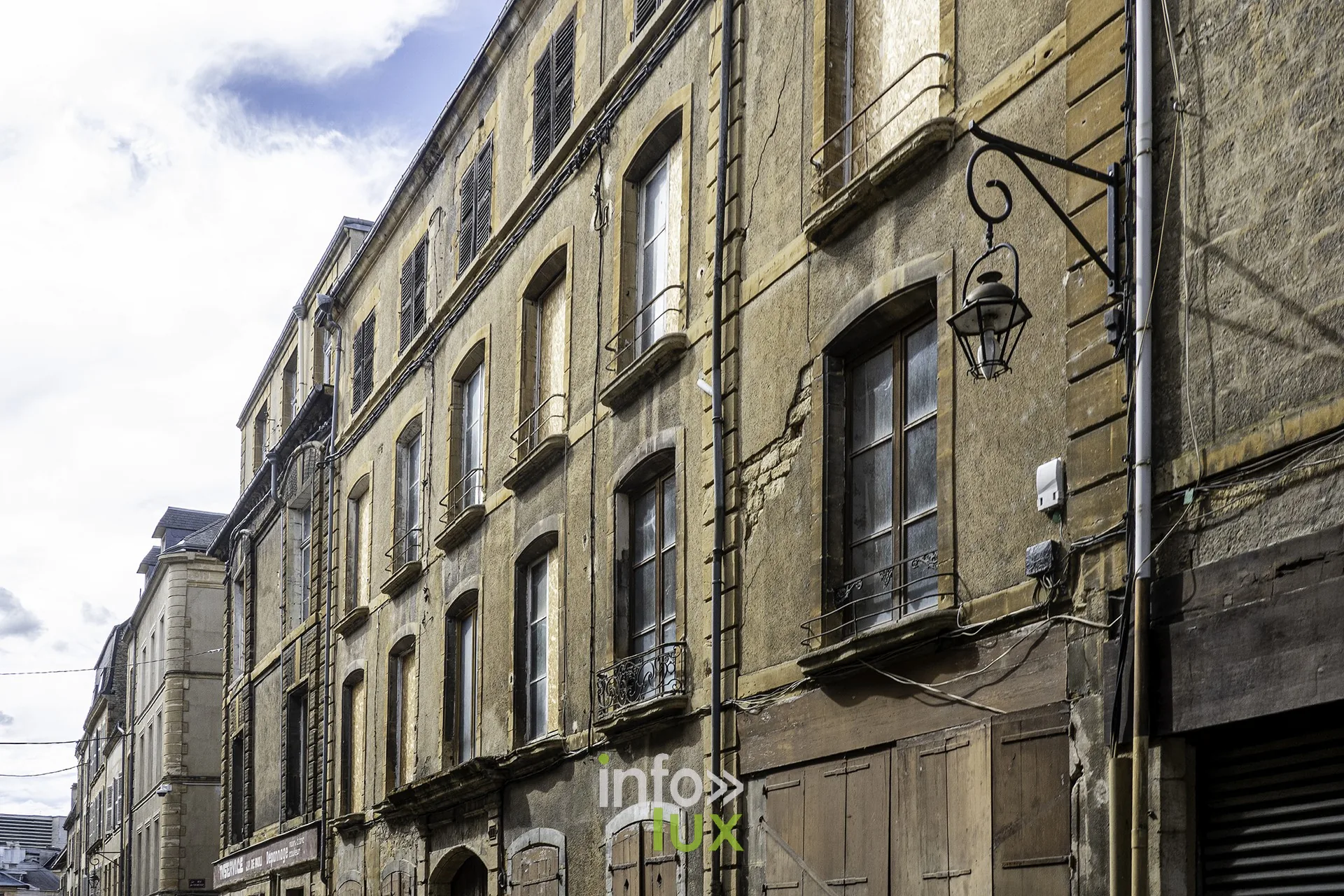 Façades anciennes en pierre avec lanterne murale dans une rue de Sedan
