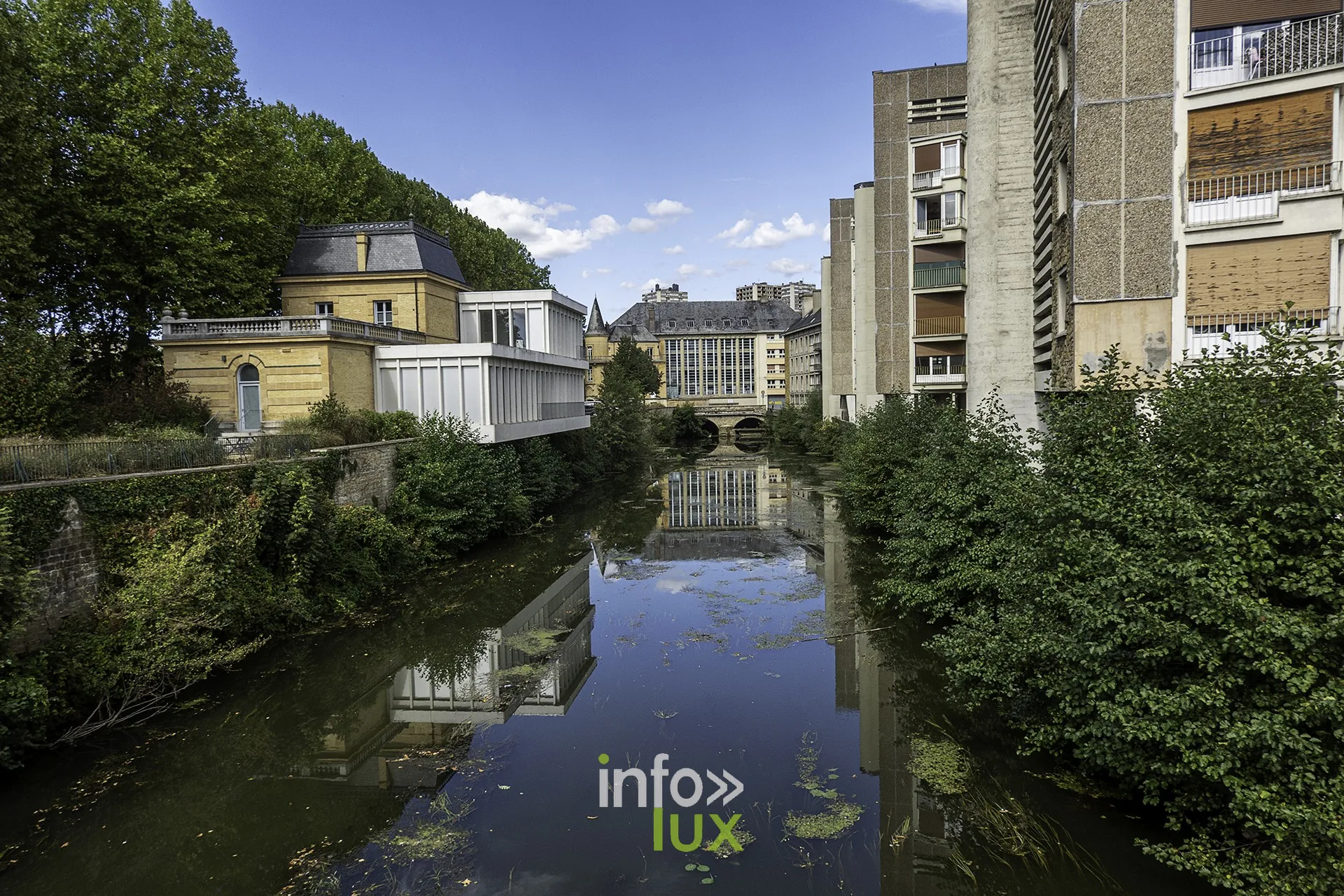 Bras d’eau entre immeubles et verdure, reflets, centre de Sedan