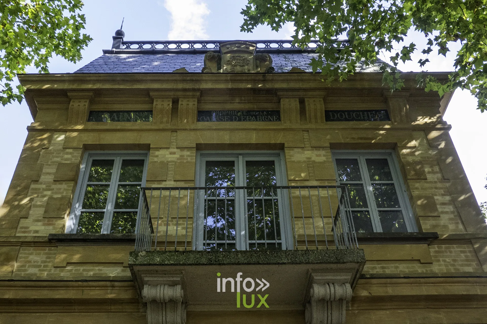 Façade ancienne à balcon en fer forgé sous les arbres, Sedan