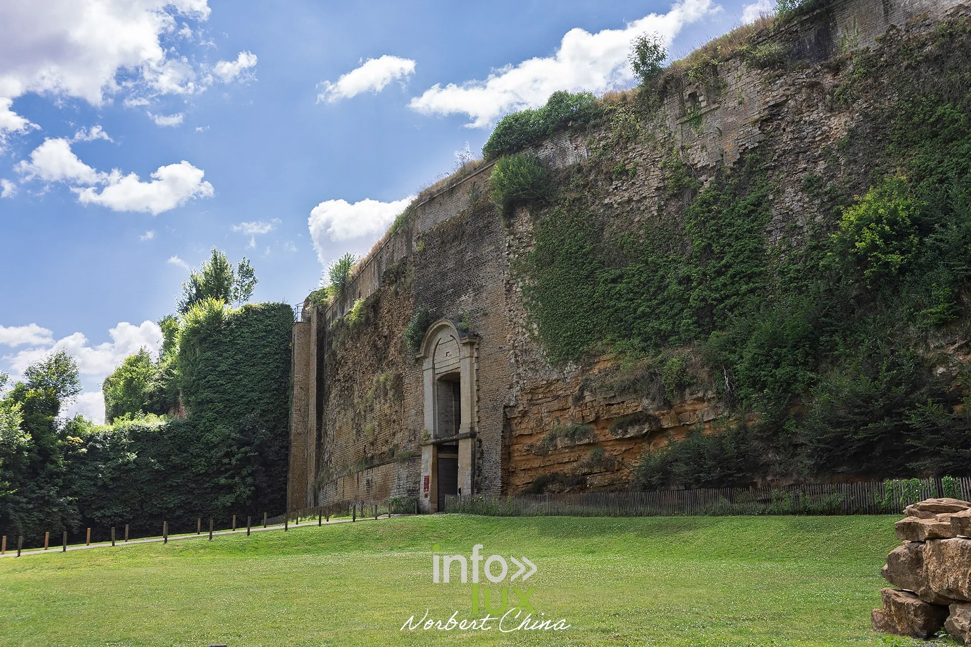 Porte monumentale dans la muraille du château fort de Sedan, pelouse au premier plan
