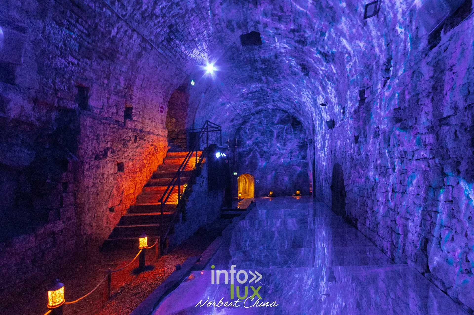 Galerie voûtée éclairée en bleu et rouge avec escalier, au château fort de Sedan (Ardennes)