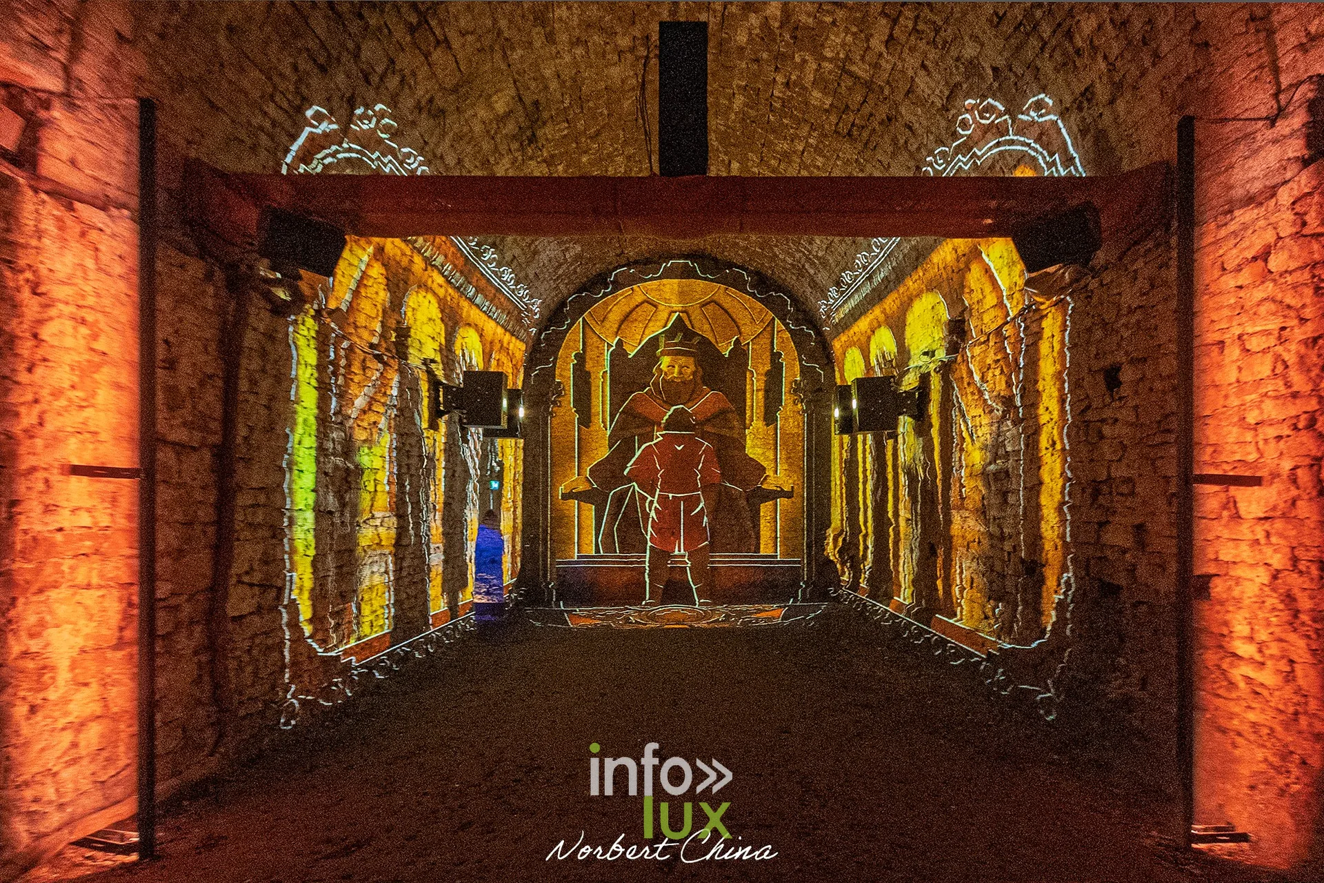 Salle voûtée baignée de lumière orange avec projection d’un personnage, au château fort de Sedan (Ardennes)