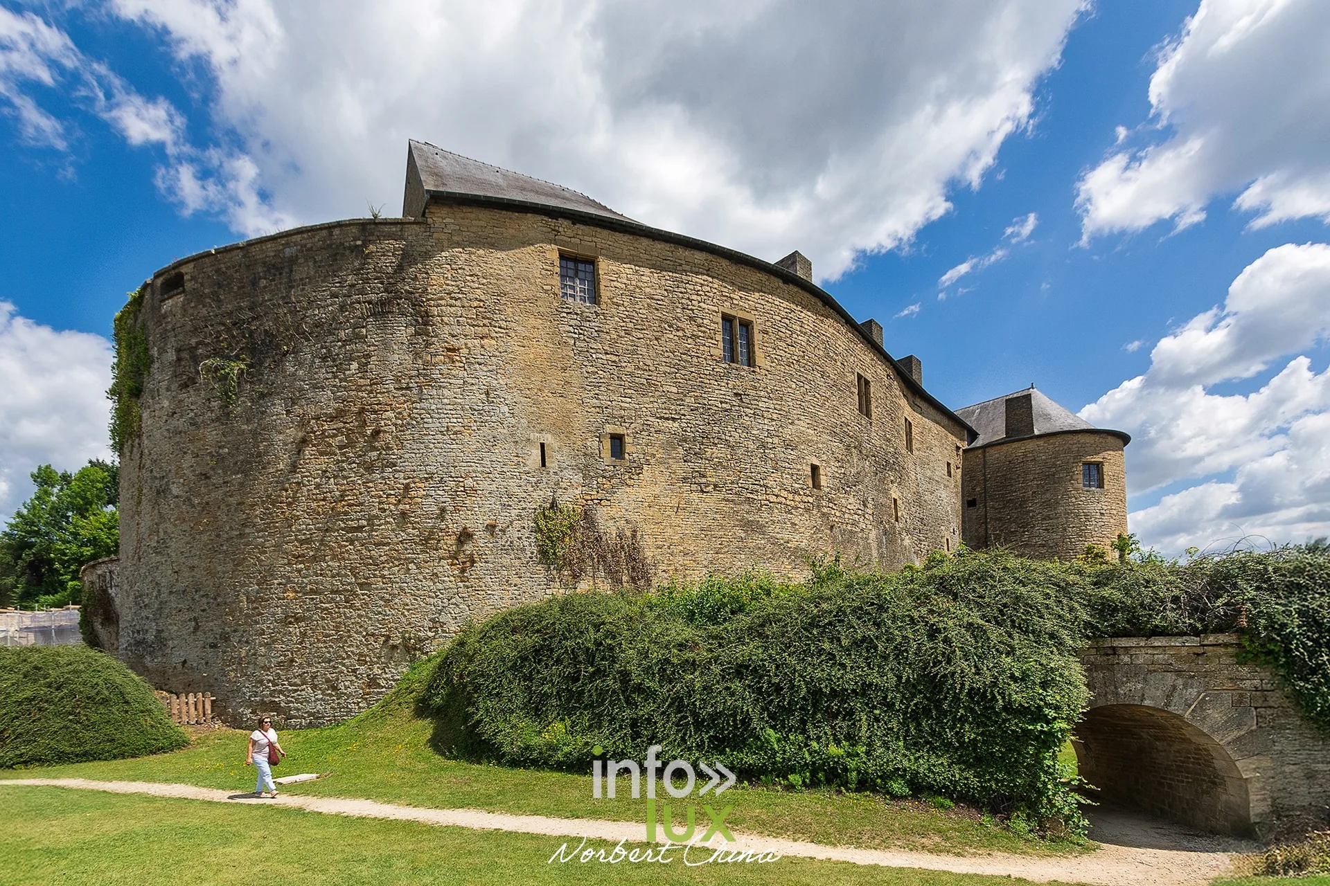 Grosse tour ronde du château fort de Sedan au-dessus d’une pelouse et d’un passage voûté