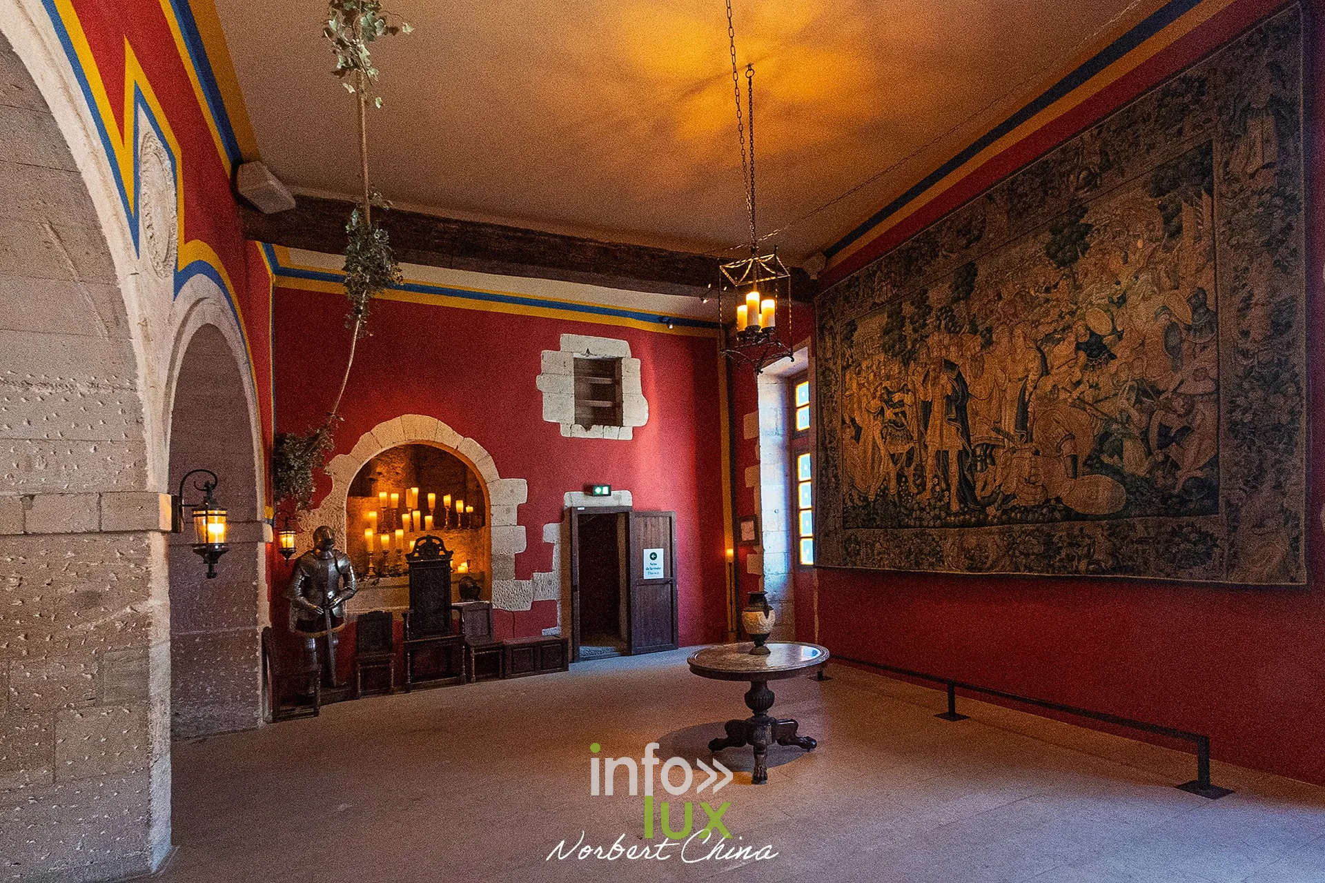 Salle aux murs rouges ornée d’une tapisserie, armure au fond, au château fort de Sedan (Ardennes)