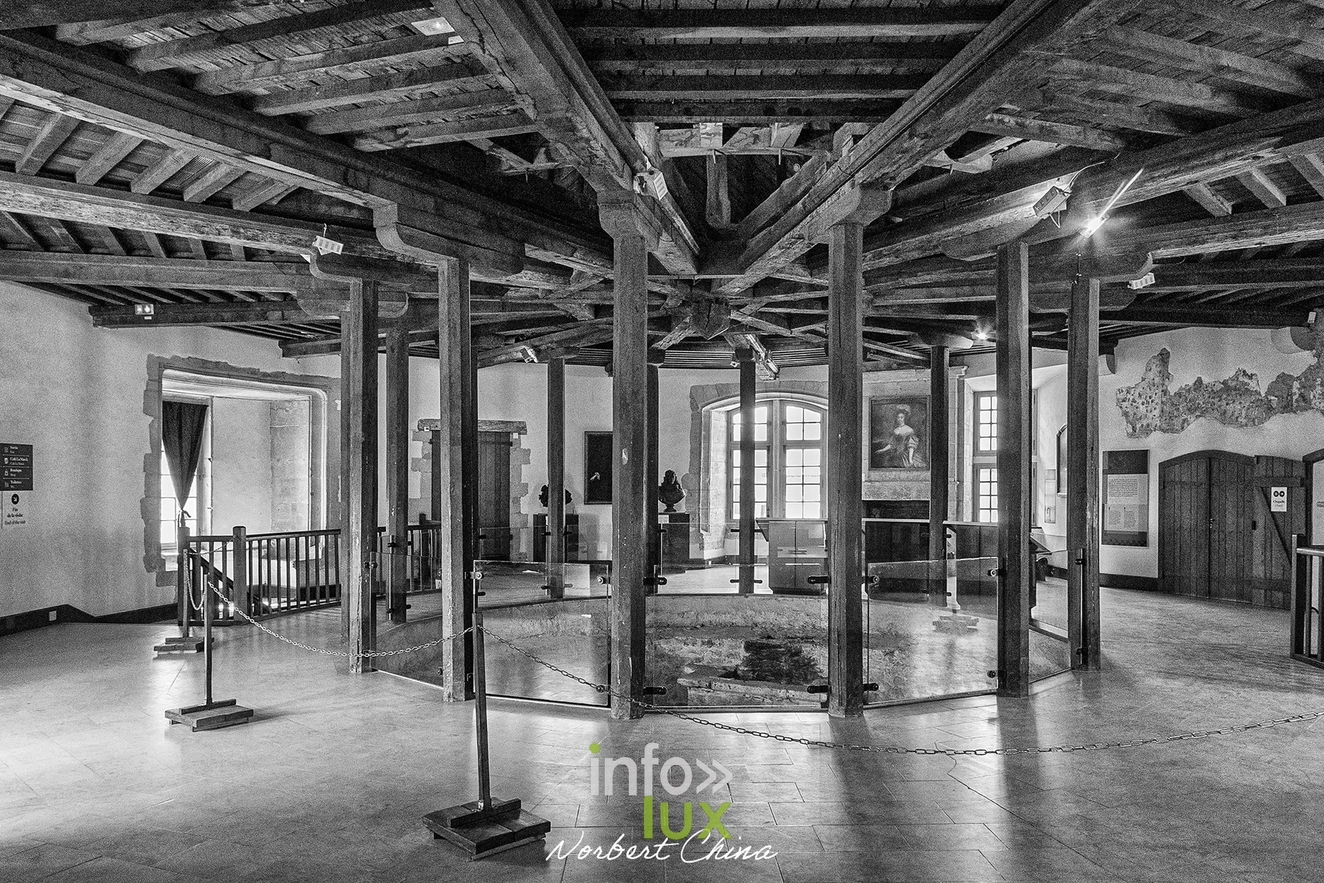 Salle à charpente et poteaux de bois avec vestiges sous plancher vitré, au château fort de Sedan (Ardennes), en noir et blanc