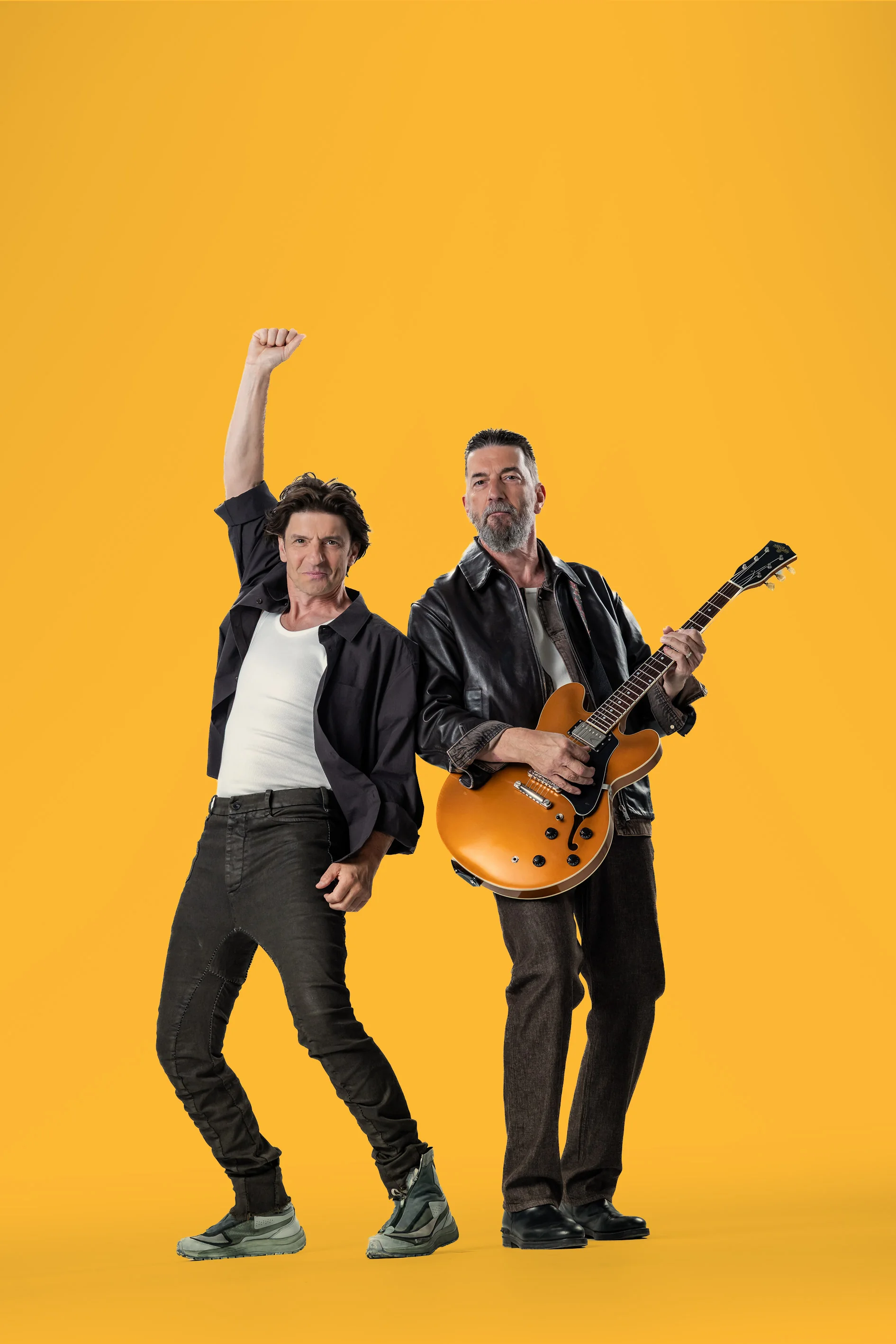 Le duo Clouseau posant sur fond jaune pour l’annonce du concert de 2027