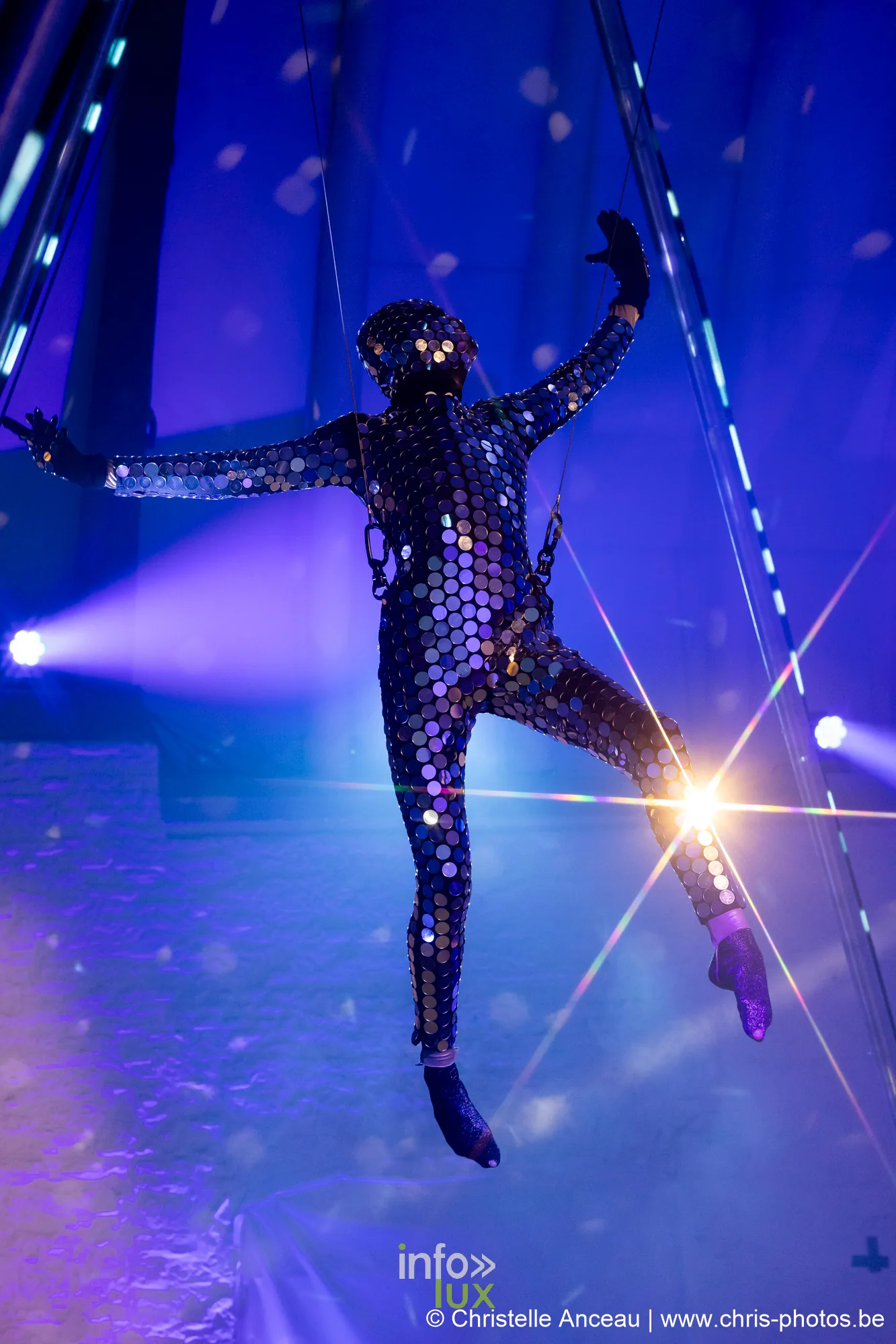 Acrobate aérien en costume de miroirs suspendu dans une lumière bleue, spectacle Monte-Cristal au Val Saint-Lambert