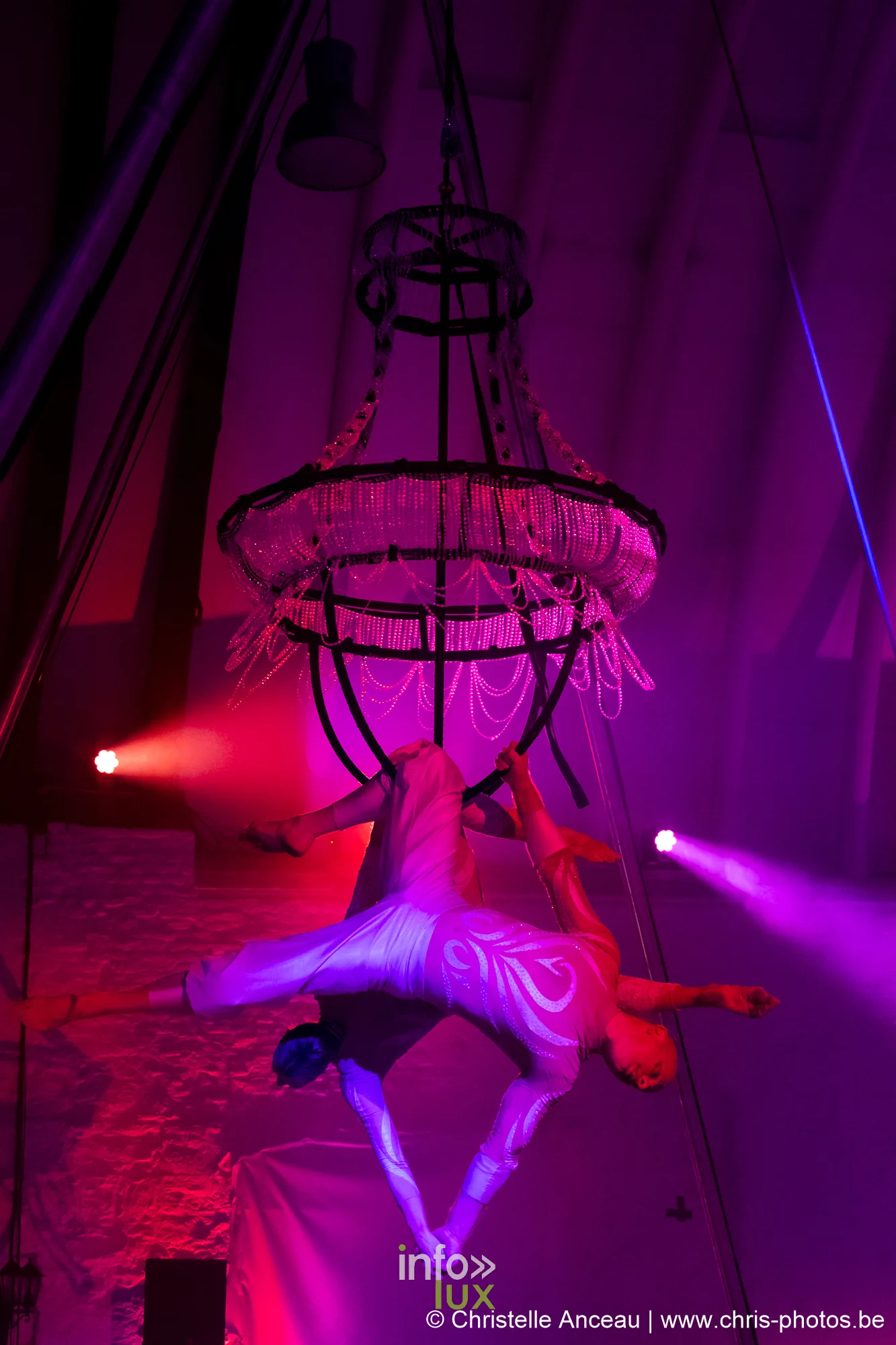 Voltigeuse aérienne sous un chandelier de cristal dans une lumière violette, spectacle Monte-Cristal au Val Saint-Lambert