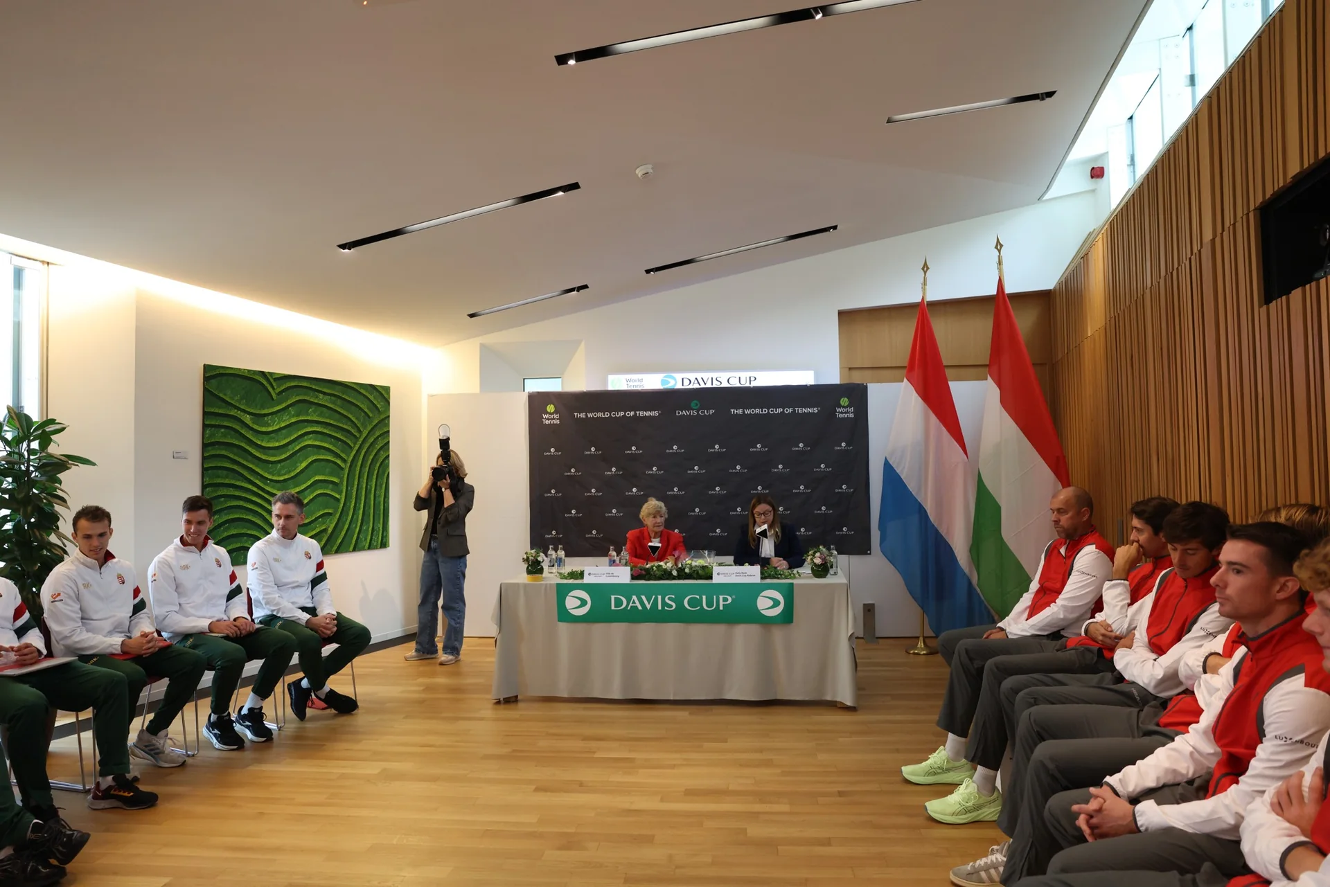 Salle du tirage au sort de la Coupe Davis Luxembourg Hongrie avec les deux equipes assises face a face et les drapeaux