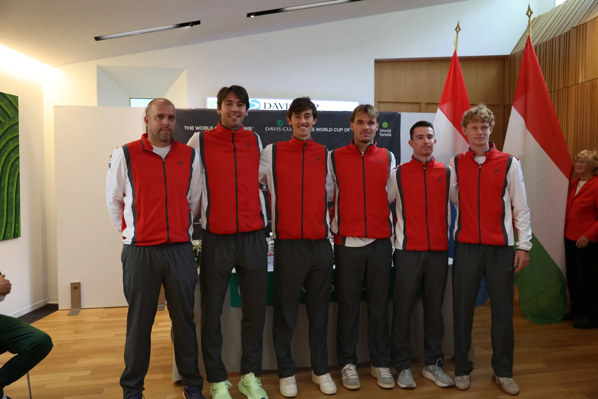 L equipe du Luxembourg de Coupe Davis en survetement rouge alignee devant les drapeaux luxembourgeois et hongrois