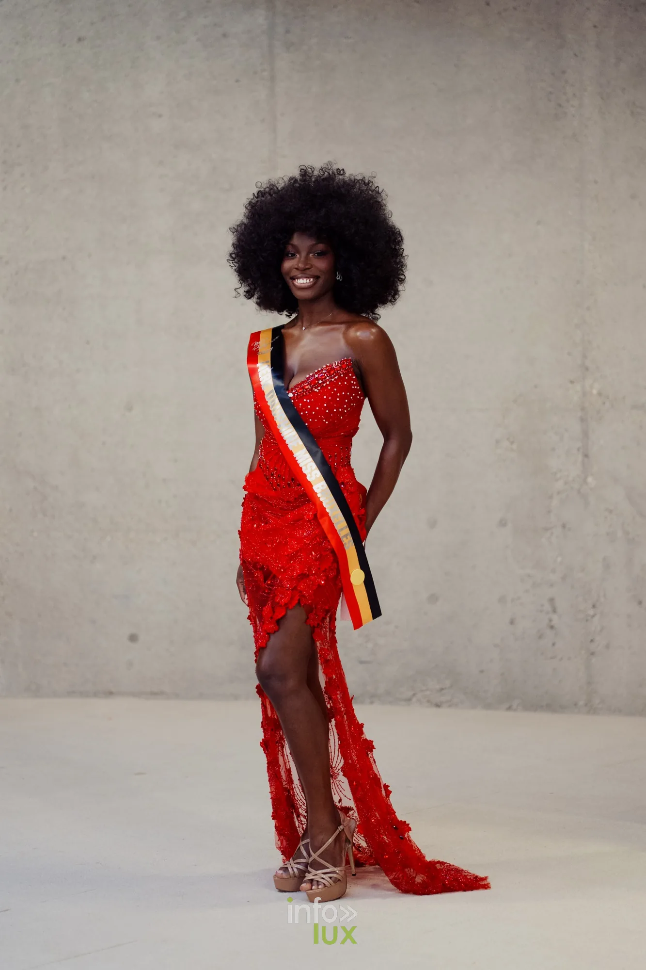 Delphine en robe rouge fendue et écharpe, photo en pied sur fond de béton