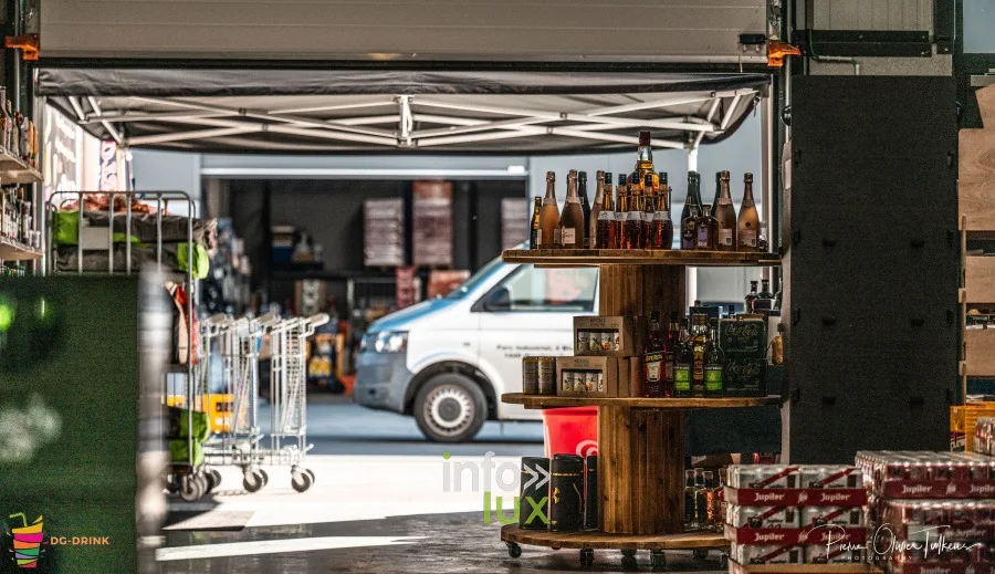 Vue de l’entrepôt DG Drink depuis le chapiteau, une camionnette et des tonneaux au premier plan