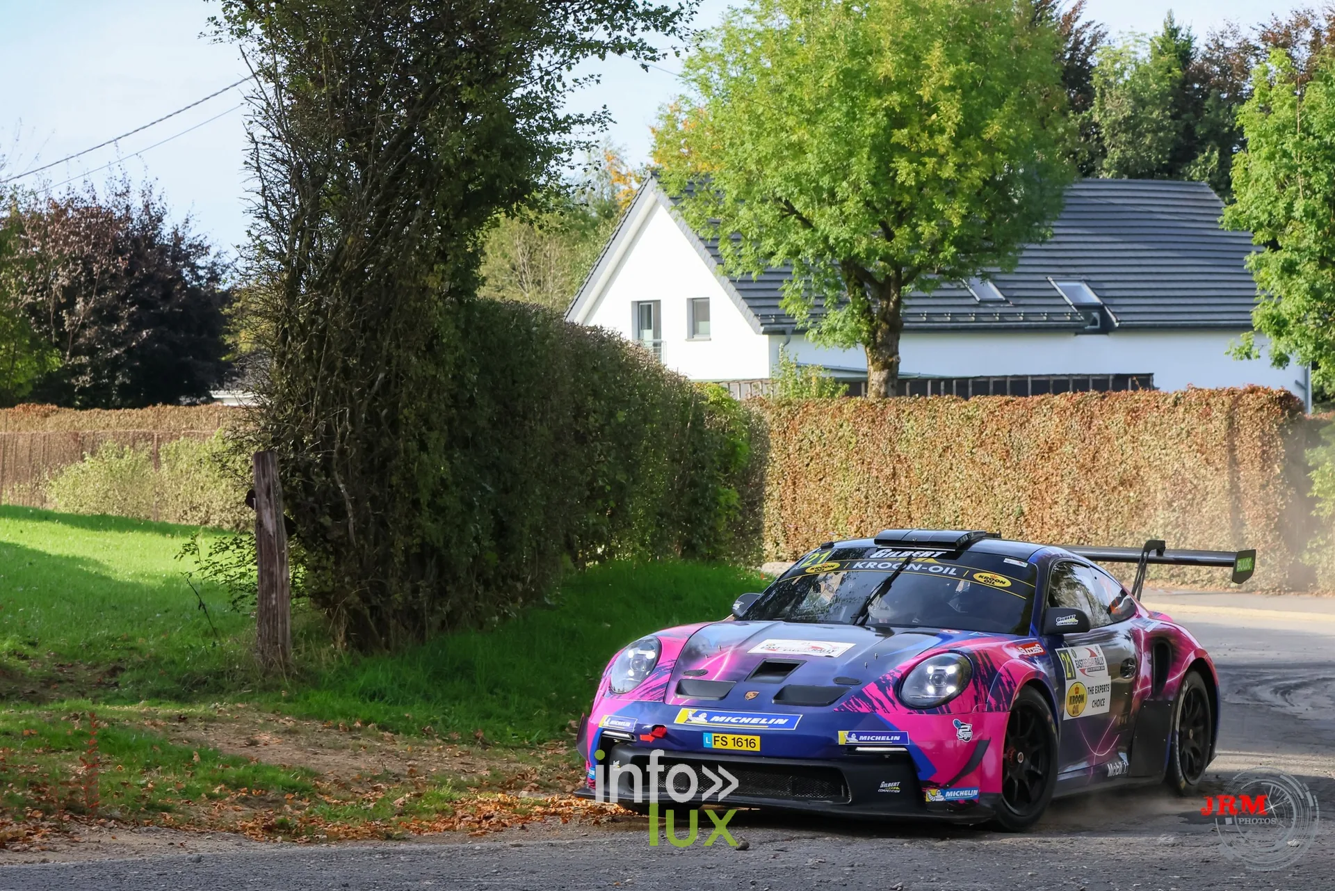 Porsche 911 GT3 de rallye rose et violette devant une maison blanche et une haie, East Belgian Rally 2026
