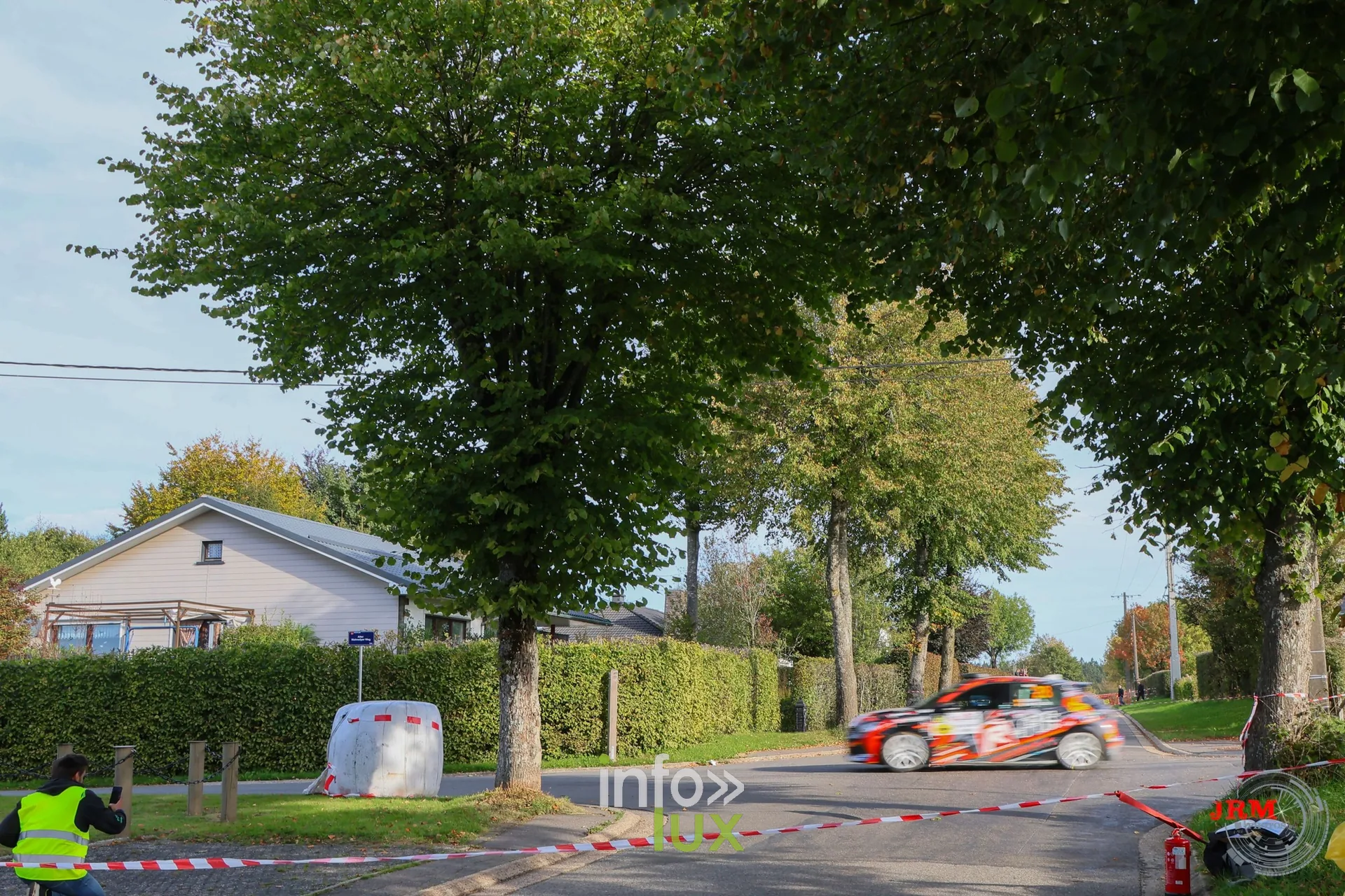 Voiture de rallye orange au bout d’une ligne droite, commissaire au premier plan, East Belgian Rally 2026