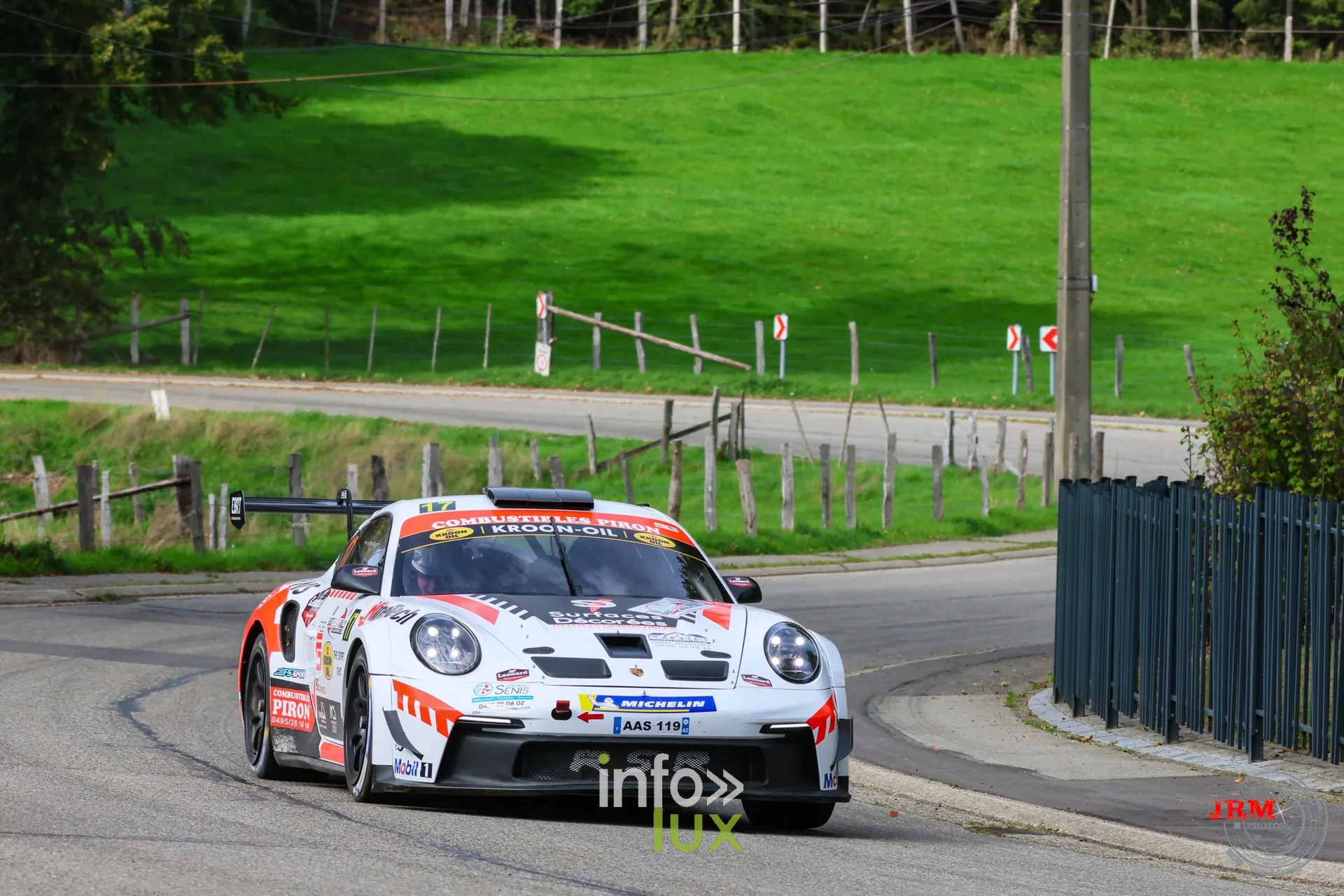 Porsche 911 GT3 de rallye blanche et rouge dans une épingle en village, East Belgian Rally 2026