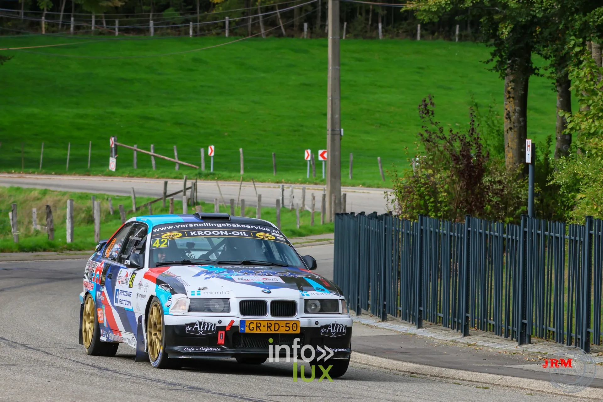BMW de rallye bleue, blanche et rouge dans une épingle en village, East Belgian Rally 2026