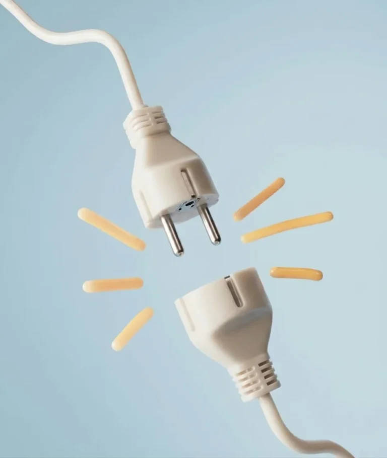 Une prise électrique débranchée, séparée de sa rallonge, sur fond bleu pâle