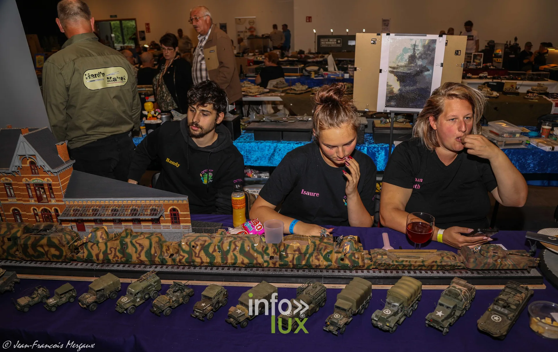 Exposantes derriere un convoi de vehicules militaires miniatures a Neufchateau