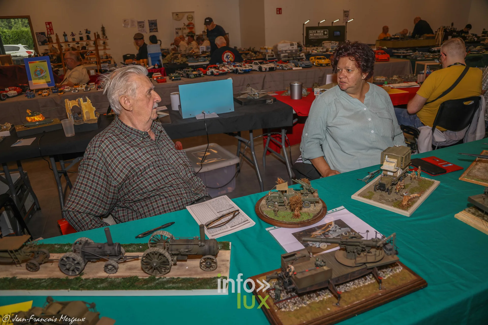 Exposants en discussion derriere des maquettes de chars a l'expo de Neufchateau