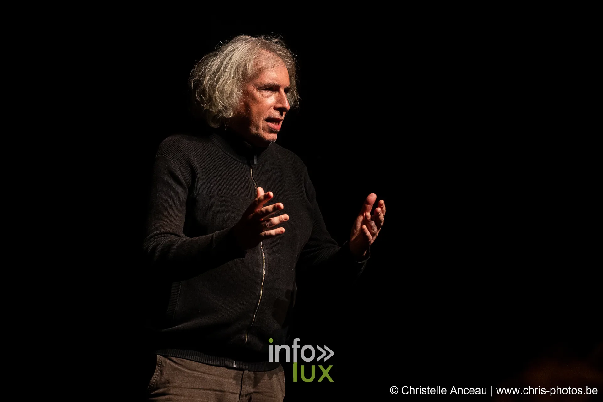 Une interprète aux cheveux blancs parle sur le plateau
