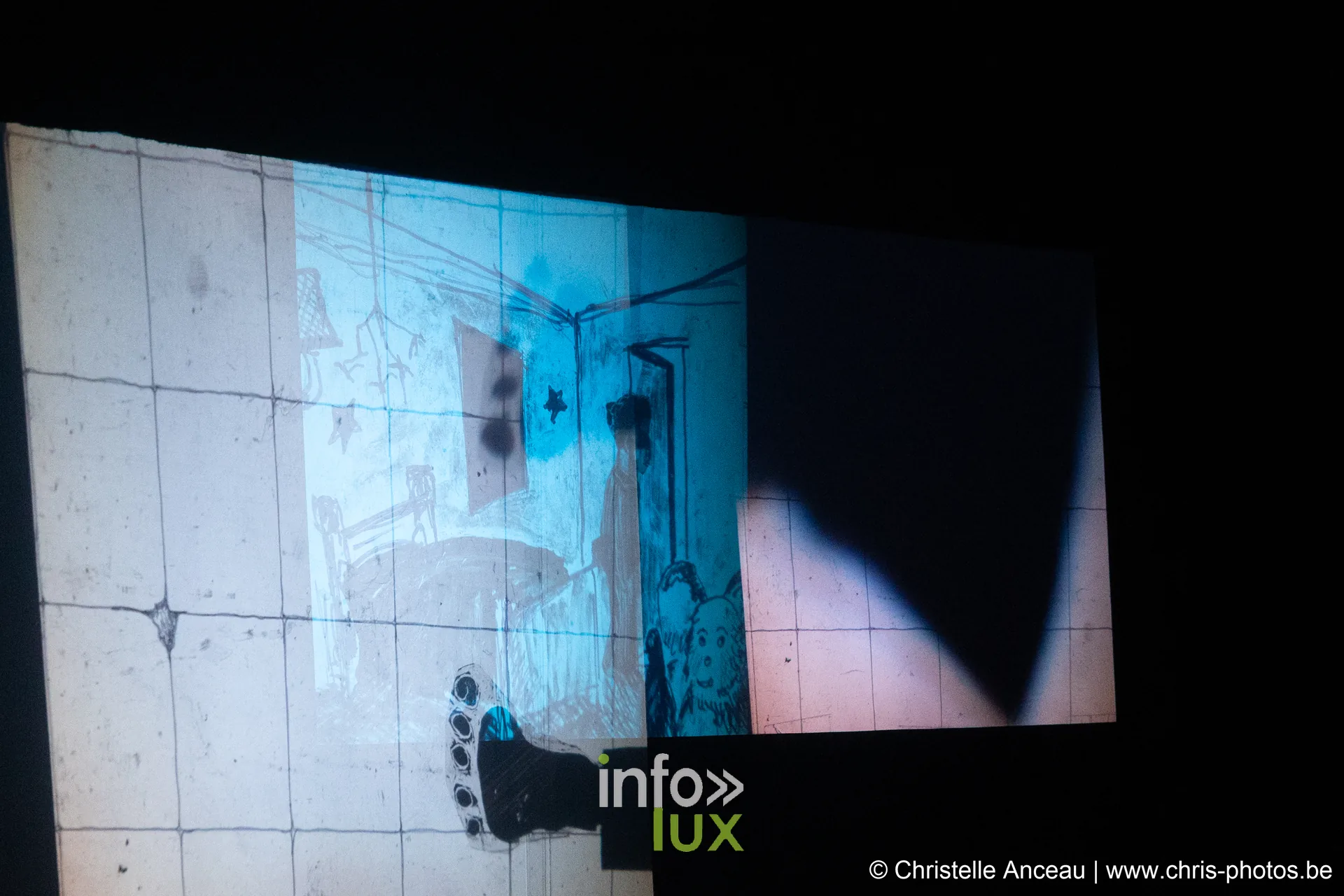 Une projection lumineuse et l'ombre d'un interprète sur le plateau