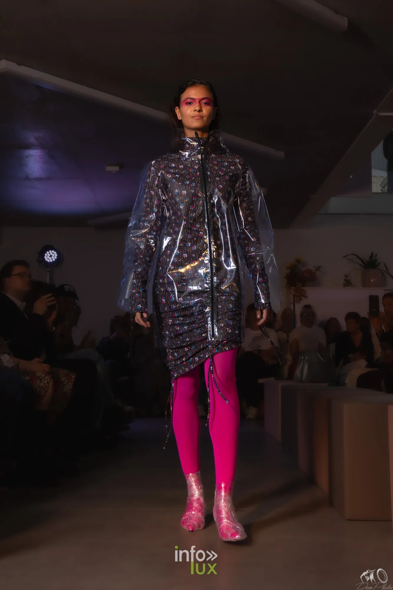 Mannequin en manteau transparent à motifs sur legging rose fuchsia et bottines roses, sur le podium du défilé Fashion in Motion à Liège