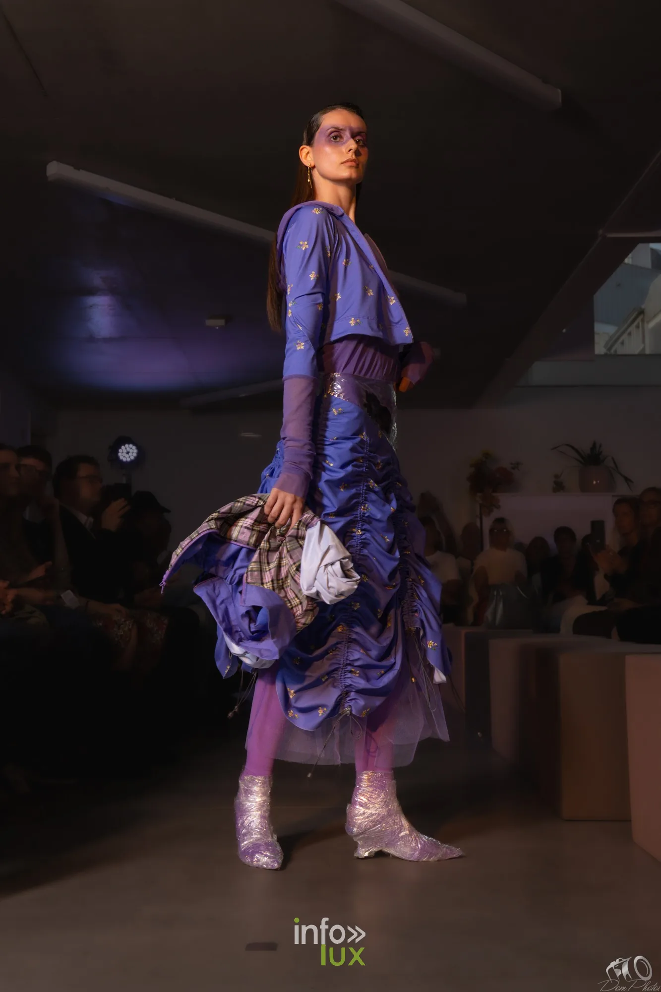 Le même ensemble violet froncé vu de trois-quarts dos, jupe drapée et sac
