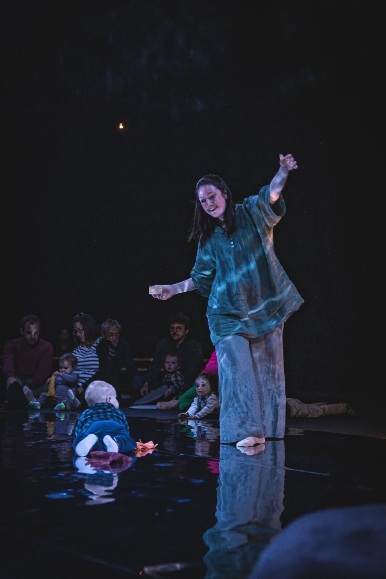Une petite fille frappe un métallophone dans la pénombre chaleureuse du spectacle Forêt paisible