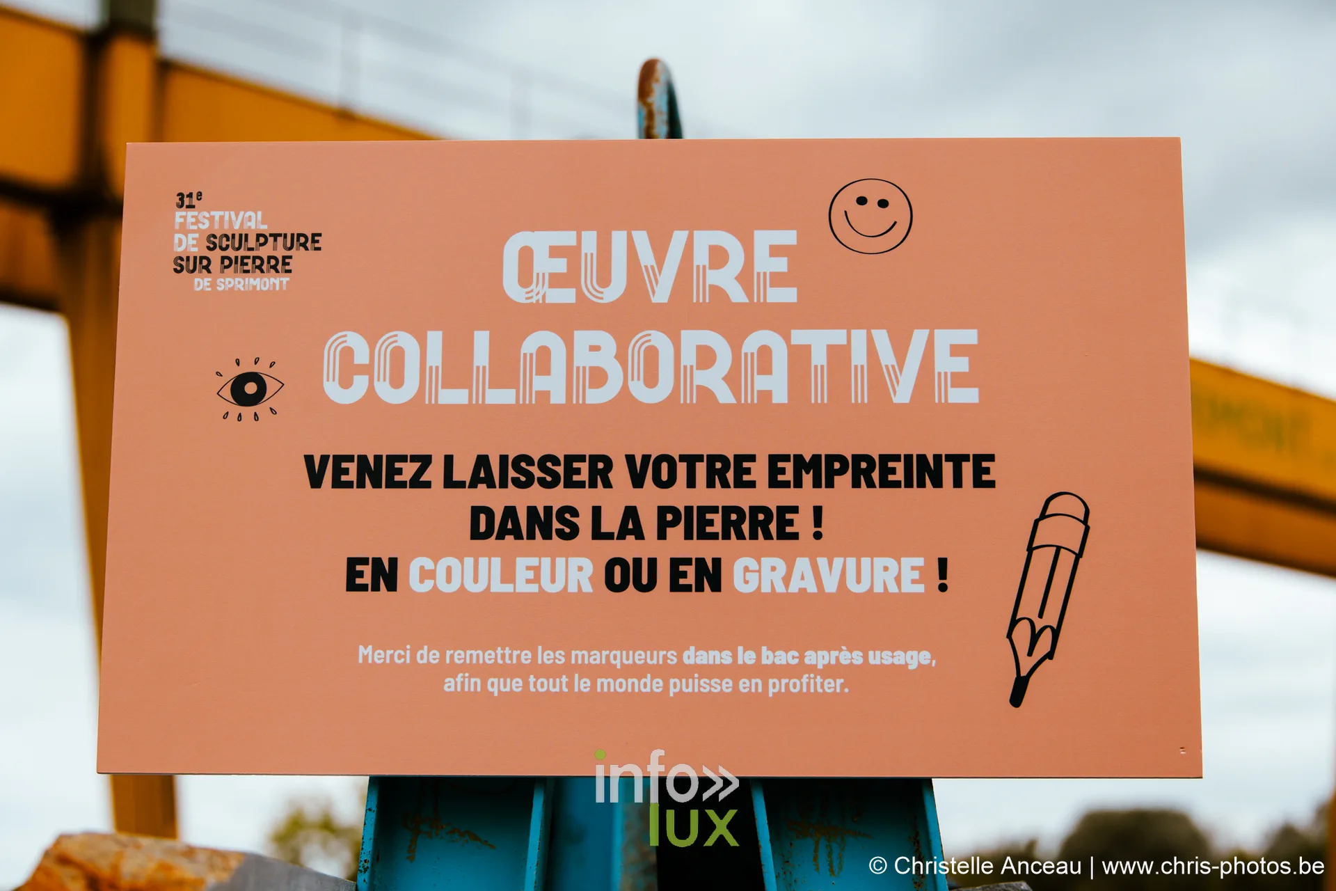 Panneau orange invitant le public à laisser son empreinte dans la pierre