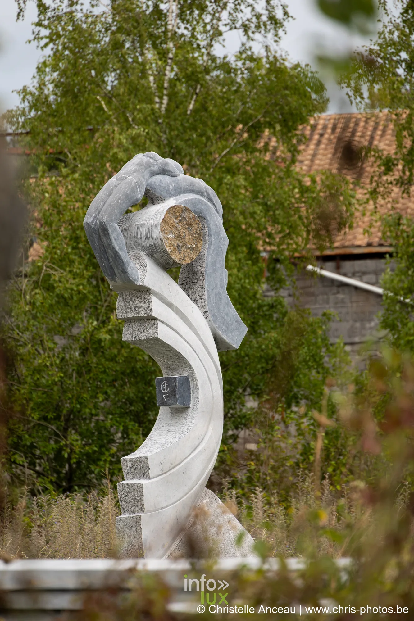 Sculpture abstraite en pierre encadrant un disque, se détachant sur le ciel