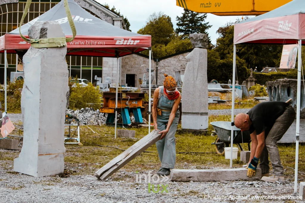 Vue d'ensemble du site du festival, barnums et blocs de pierre en cours de taille
