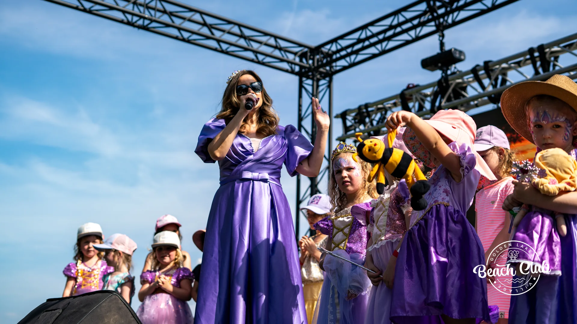 Chanteuse en robe mauve entouree d enfants deguises sur la scene du Beach Club