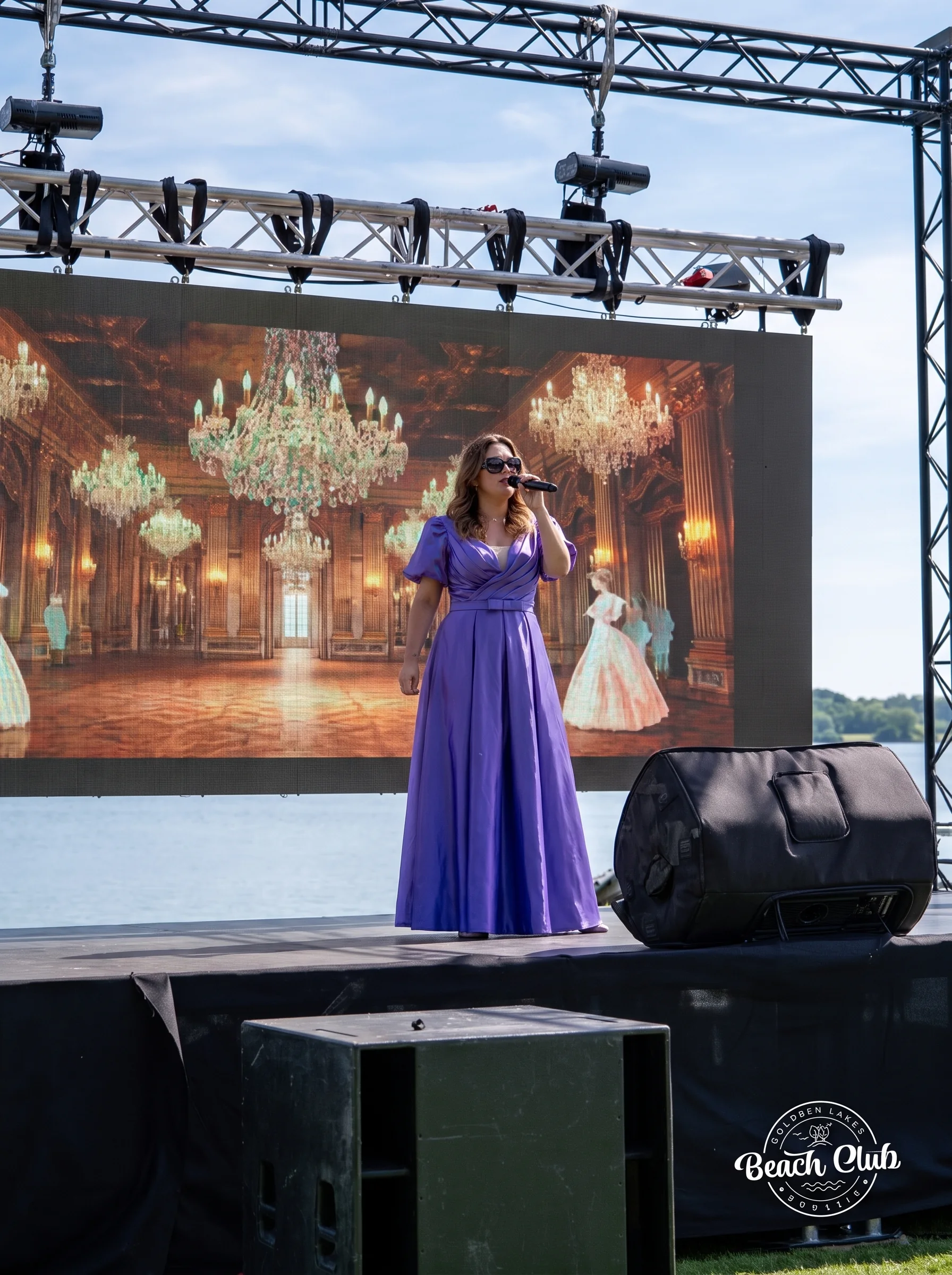 Chanteuse sur scene devant un ecran geant representant une salle de bal