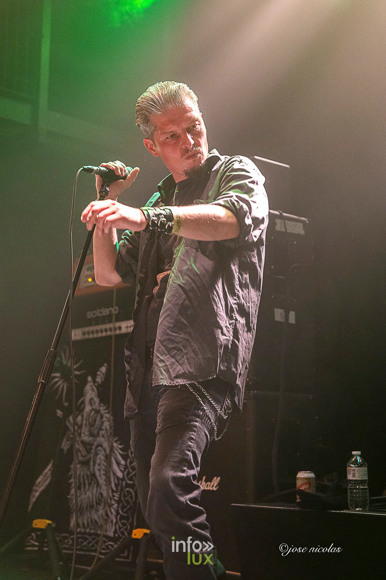 Le chanteur de Goliathus dans un halo de lumière verte, bras tendu
