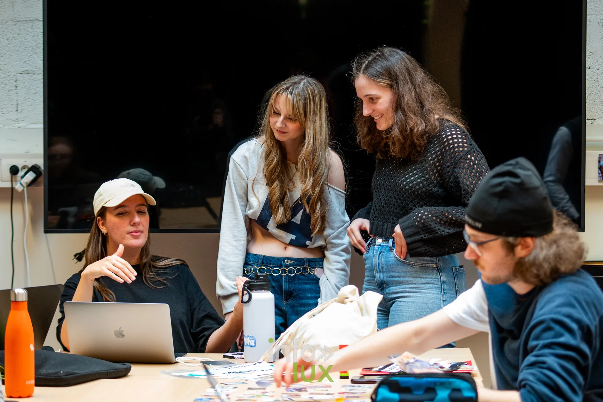 Étudiants réunis autour d’une table de travail avec ordinateurs et documents, projet collectif à la HEAJ