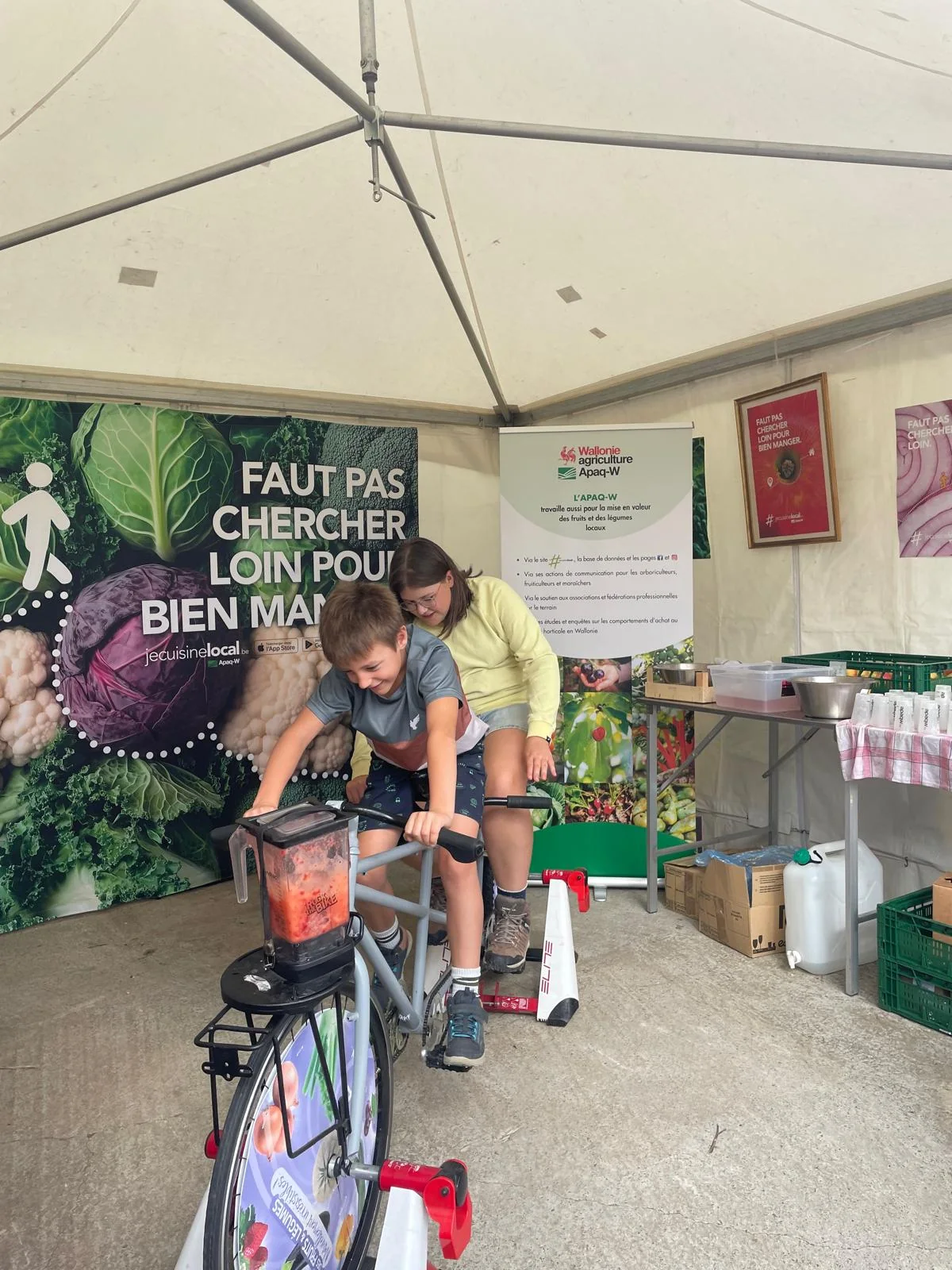 Enfants pedalant sur le Velosmoothie au stand Apaq-W des Hortifolies 2026 de Gembloux