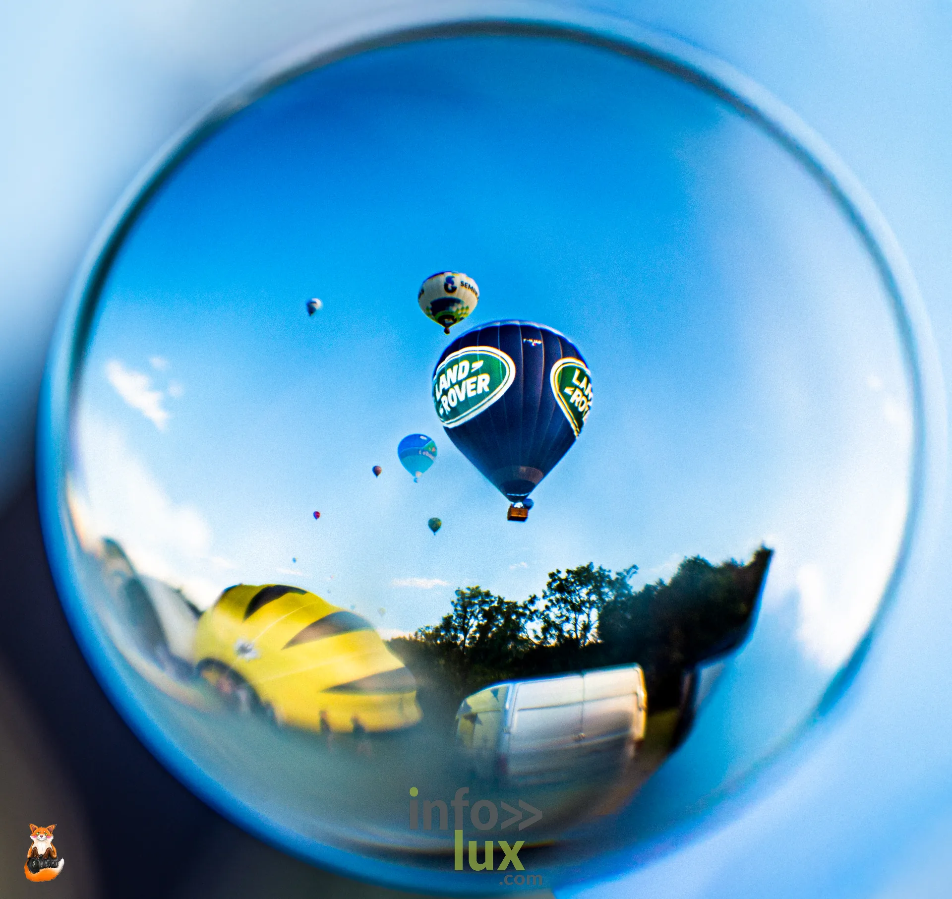 Montgolfières et paysage reflétés dans une sphère de verre, à Hotton