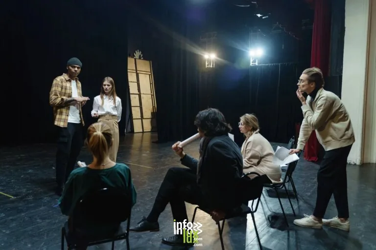 Des acteurs répétant sur scène sous les conseils du directeur dans un théâtre pour une performance en direct.